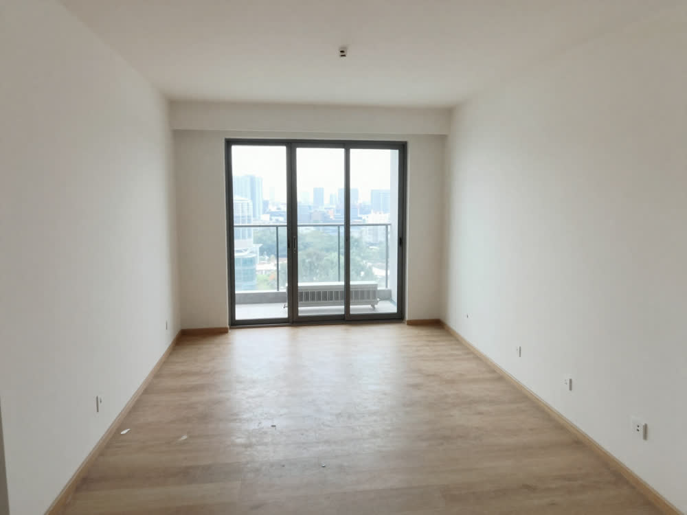 Empty high-rise condo living room with balcony doors and city view awaiting paint