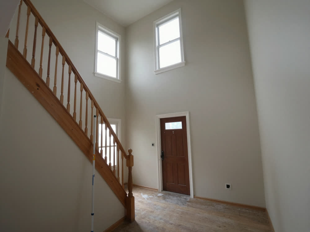 Two-storey open foyer and staircase with high blank walls awaiting paint